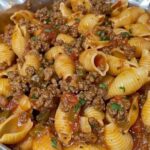 A flavorful dish of pasta shells mixed with seasoned ground beef and marinara sauce, garnished with fresh parsley