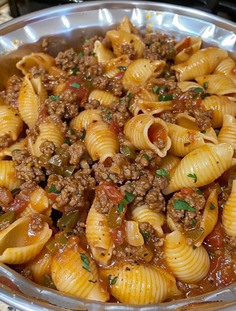 A flavorful dish of pasta shells mixed with seasoned ground beef and marinara sauce, garnished with fresh parsley